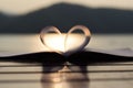 Heart shape from paper book at sunset with light reflection on a water surface (vintage background)