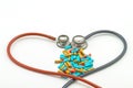 Heart shape of pink and blue stethoscope and colorful pill on w