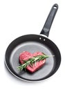 Heart shape raw fresh beef steak with rosemary stick on frying pan isolated on white Royalty Free Stock Photo