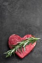 Heart shape raw fresh beef steak with rosemary stick on metal background Royalty Free Stock Photo