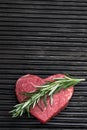 Heart shape raw fresh beef steak with rosemary stick on metal grill background Royalty Free Stock Photo