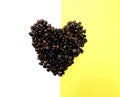 Heart shape roasted coffee beans brown and dark seed variation on half white and yellow background Royalty Free Stock Photo