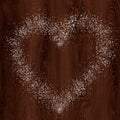 Heart shape from snow on dark wood background