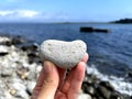 Heart shape stone in girls hand against background of beach. Summer sunny day. Love, wedding and Valentine day concept Royalty Free Stock Photo