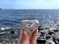 Heart shape stone in girls hand against background of beach. Summer sunny day. Love, wedding and Valentine day concept Royalty Free Stock Photo