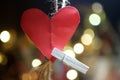 Heart shape on a string. Red blank paper for your notes with love symbol hanging on rope with white wooden clip on colorful bokeh Royalty Free Stock Photo