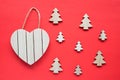 Heart shape wooden sign board frame hanging on a rope and little fir trees on red background Royalty Free Stock Photo