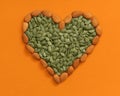 heart-shaped almonds and pumpkin seeds on orange background