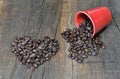 Heart shaped in beans coffee next to a spilled red cup full of beans