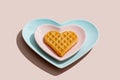 Heart shaped  belgian waffles on blue plate on pink background. Happy Valentine`s Day. Close-up Royalty Free Stock Photo