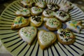 Heart-shaped biscuits pastry of different shapes with icing and colorful sugar decor on plate close-up. Holidays homemade bakery c Royalty Free Stock Photo