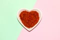 heart-shaped bowl with ajvar, traditional balkan dish of roasted peppers and eggplant, pastel blue-pink background