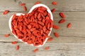 Heart shaped bowl of goji berries on wood Royalty Free Stock Photo