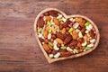 Heart shaped bowl with mixed nuts on wooden table top view. Healthy food and snack Royalty Free Stock Photo