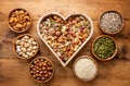 Heart shaped box and bowls full of nuts and seed on rustic table Royalty Free Stock Photo