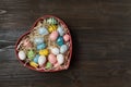 Heart shaped box with colorful bright Easter eggs. Dark wooden background. Top view Royalty Free Stock Photo