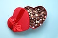 Heart shaped box with delicious chocolate candies on light blue background, top view Royalty Free Stock Photo
