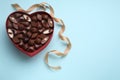 Heart shaped box with delicious chocolate candies and ribbon on light blue background, flat lay. Space for text Royalty Free Stock Photo