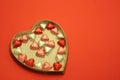 Heart shaped box with foil wrapped candies on red background