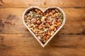 Heart shaped box full of nuts and seed on rustic table Royalty Free Stock Photo