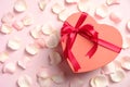 Heart shaped box with red ribbon bow and white roses petals on pink table, top view. Happy Valentines Day, Mothers Day, birthday Royalty Free Stock Photo