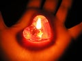 Heart shaped burning red candle in the palm of the hand in the dark. Valentine`s day concept. Unshared love concept