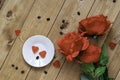 Heart-shaped candies on a plate and red roses on a wooden background.Romantic, St Valentines Day concept Royalty Free Stock Photo