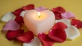 Heart-shaped candle surrounded by rose petals Royalty Free Stock Photo
