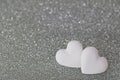 2 heart shaped candy pills on silver glittery background