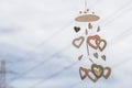 Heart shaped ceramic wind chimes hanging on window and defocused sky in background. Royalty Free Stock Photo