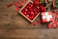 Heart shaped chocolate candies, bouquet and gift box on wooden table, flat lay. Space for text Royalty Free Stock Photo