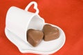 Heart shaped chocolates and cup on red background