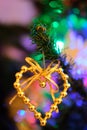 Heart shaped Christmas decoration hanging on a nicely illuminated Christmas tree