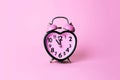 Heart shaped clock on pink background.