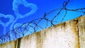 Heart-shaped cloud in the sky behind barbed wire