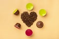 Heart shaped coffee beans and capsules around on beige background