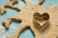 Heart-shaped cookie cutter on raw dough Cyan tabletop Royalty Free Stock Photo