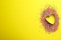 Heart shaped cookie cutter and sprinkles on yellow background, flat lay with space for text. Confectionery decor Royalty Free Stock Photo