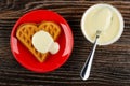 Heart shaped cookies poured condensed milk in red saucer, spoon in bowl with condensed milk on table. Top view Royalty Free Stock Photo