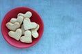 Heart shaped cookies in red plate on gray concrete backdrop. Valentine`s day homemade treats. Royalty Free Stock Photo