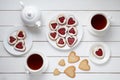 Heart shaped cookies for Valentines day with teapot and two cups of tea on white wooden background. Royalty Free Stock Photo