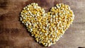 heart shaped corn kernels on brown wooden table for making popcorn