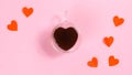 Heart-shaped cup is filled with coffee near paper butterfly hearts. The concept of love, valentine`s holiday or favorite drinks