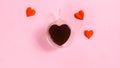 Heart-shaped cup is filled with coffee near paper butterfly hearts. The concept of love, valentine`s holiday or favorite drinks