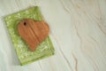 A heart-shaped cutting board made of beech wood and a beautiful green linen napkin on a pastel green marble background. Royalty Free Stock Photo
