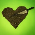 Heart-shaped earth with a knife on a green background Royalty Free Stock Photo