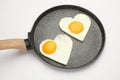 Heart shaped fried eggs in frying pan isolated on white Royalty Free Stock Photo