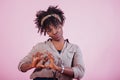 Heart shaped gesture. Attractive afro american woman in casual clothes at pink background in the studio