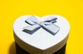 Heart-shaped gift box with a blue bow on top. Blue gift box isolated on yellow background. Close-up photo. Blur Royalty Free Stock Photo