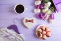 Heart shaped gift box, bouquet of purple and white tulips, cup of coffee, strawberry in chocolate and hanger with clothes on lilac Royalty Free Stock Photo